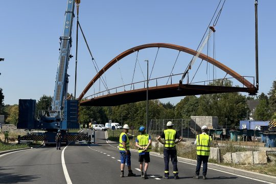 Bauarbeiter und Kräne bei der Errichtung der neuen Fahrrad- und Fußgängerbrücke