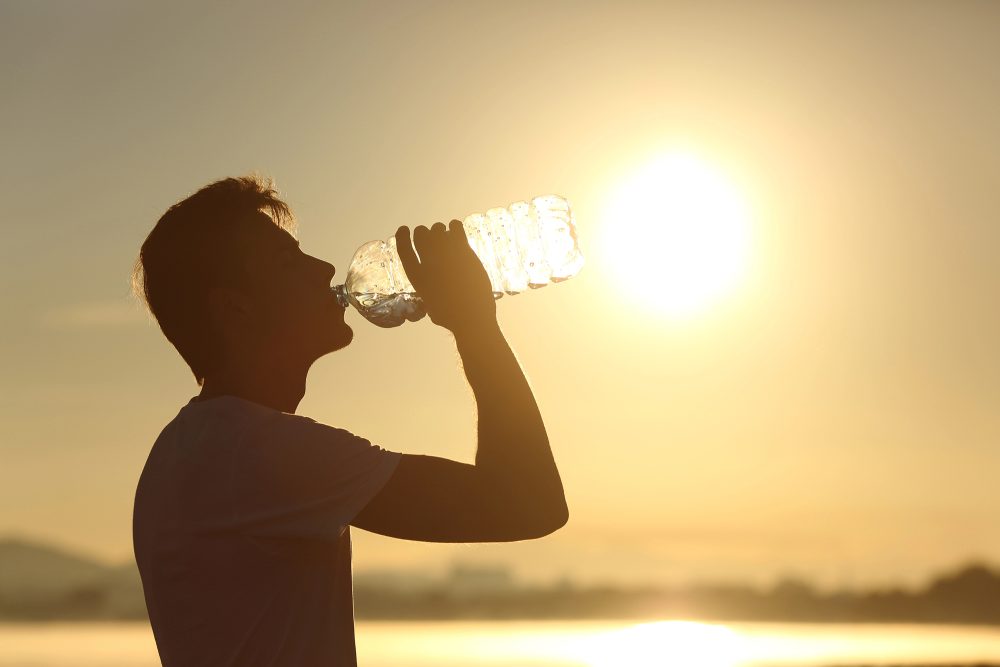 Mann trinkt bei sonnigem Wetter Wasser aus einer Plastikflasche