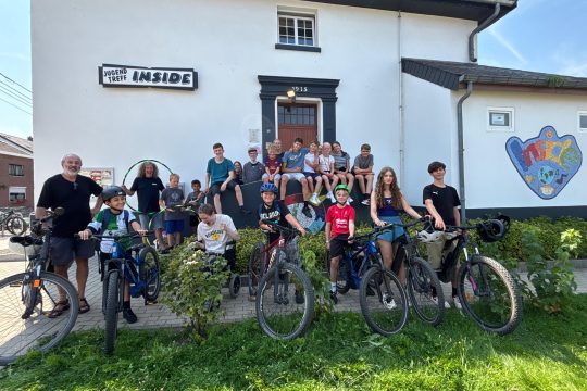 Teilnehmer des Sommerlagers posieren auf den Fahrrädern vor dem Jugendtreff Inside