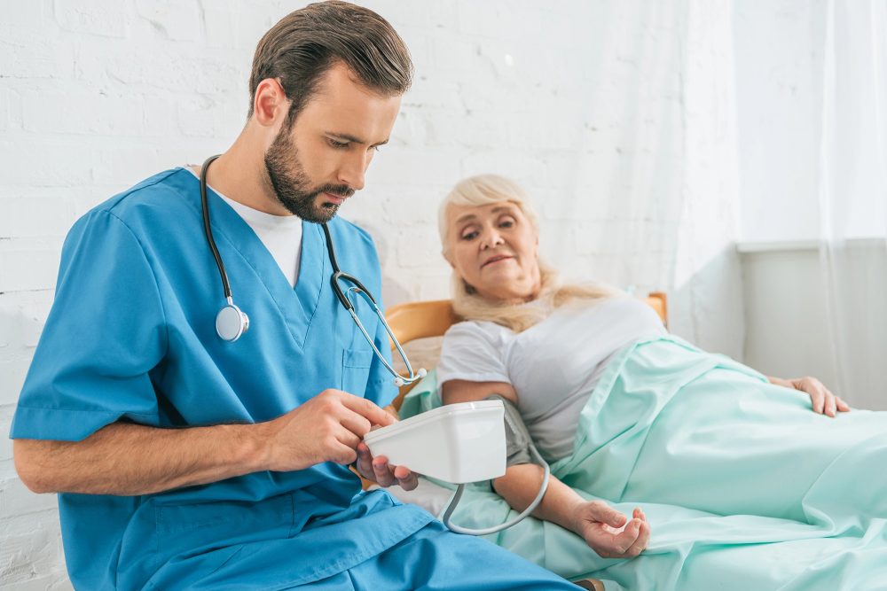 Krankenpfleger misst Blutdruck einer Seniorin