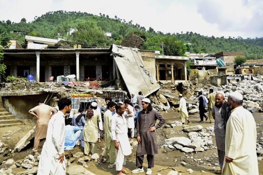 Nach Sturzfluten im Norden Pakistans versammeln sich Dorfbewohner vor einem zerstörten Haus