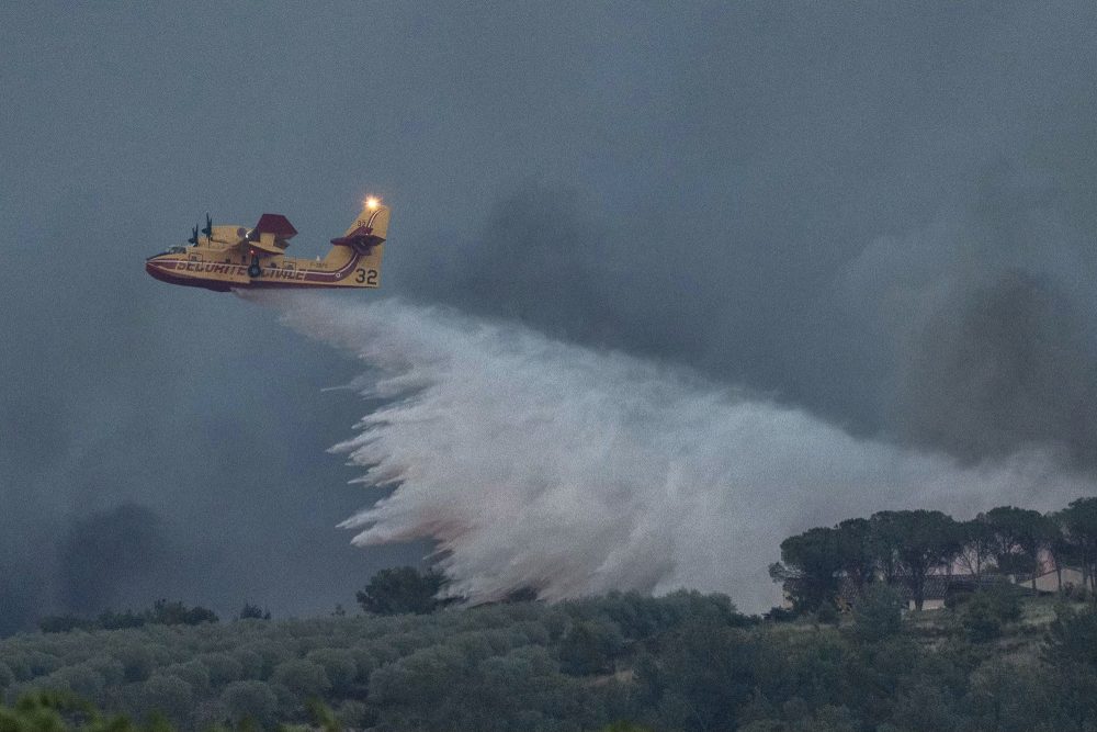 Ein Löschflugzeug wirft über einem Waldgebiet Wasser ab