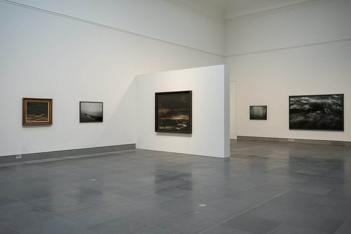 Mehrere Werke hängen an den Wänden in der Ausstellung