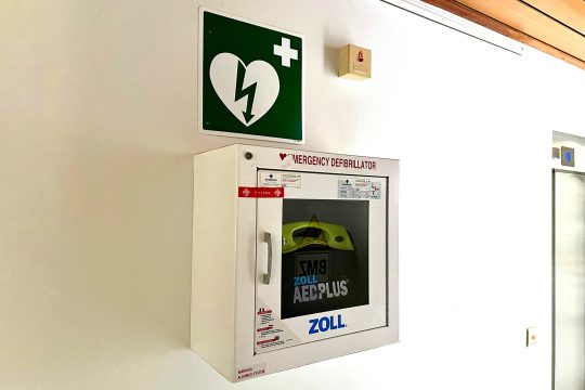 Defibrillator mit Hinweisschild im BRF-Foyer