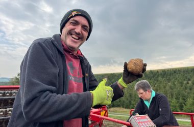 Kartoffelbauer Robert Wangen hält eine Kartoffel in der Hand und lacht