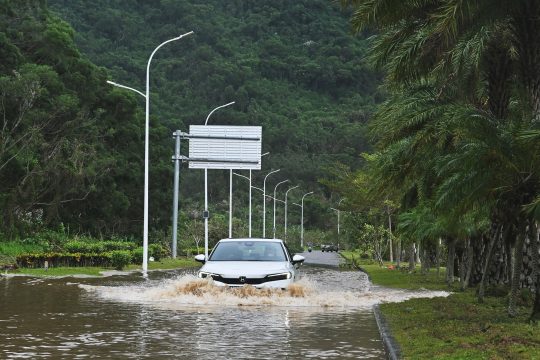 Ein Auto fährt durch eine überflutete Straße im Süden von China