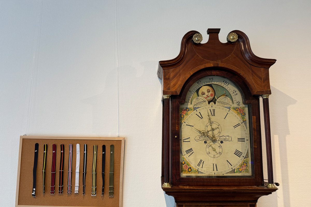 Armbänder hängen an einer Pinnwand, daneben ist eine Standuhr