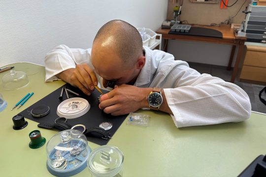 Yves Schmitz sitzt am Arbeitstisch und zerlegt eine Uhr