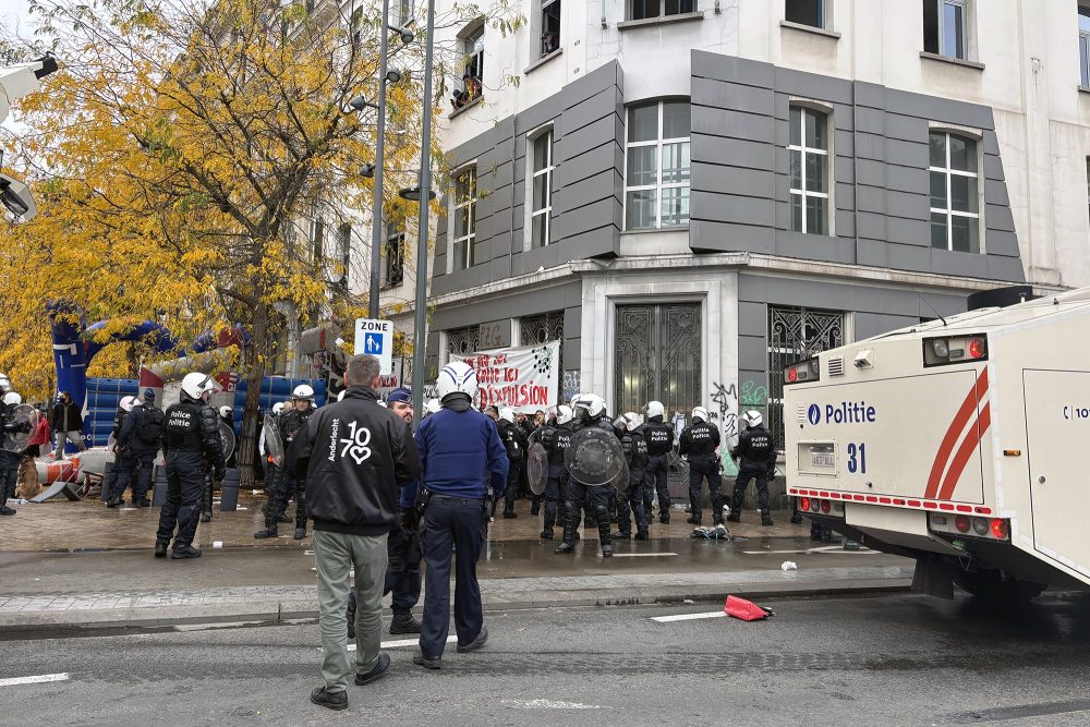 Menschen und ein Polizeifahrzeug vor dem besetzten Haus in Anderlecht