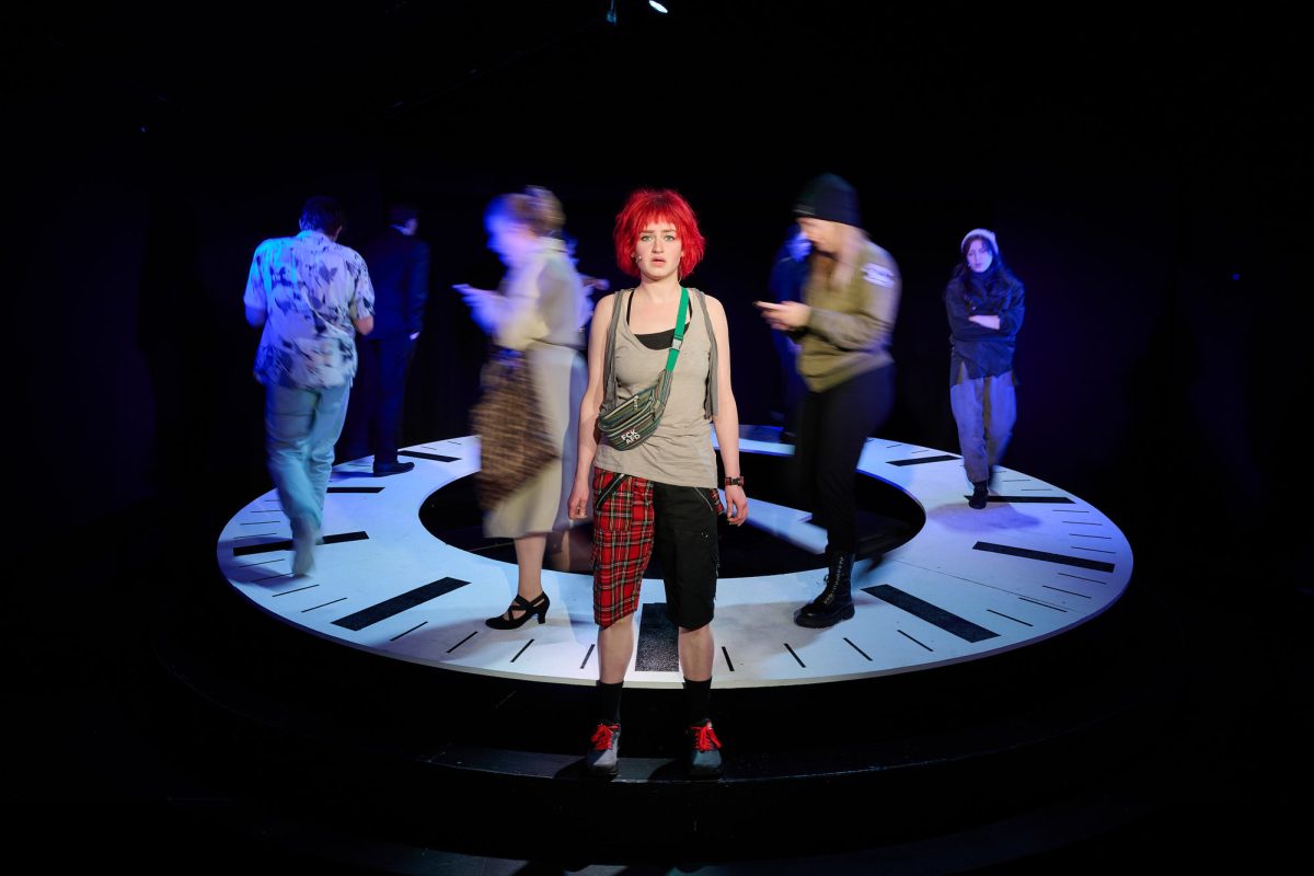 "Lola rennt" im Das-Da-Theater: Lola vor der Uhr, auf der Menschen wandern