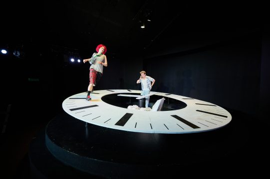 Lola rennt auf dem Ziffernblatt der riesigen Uhr