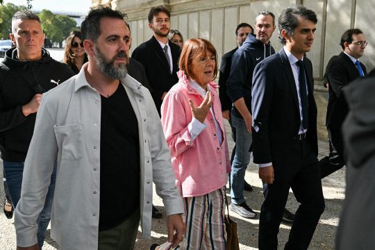 Das Opfer bei der Ankunft, umringt von Sicherheitsbeamten und ihrem Sohn