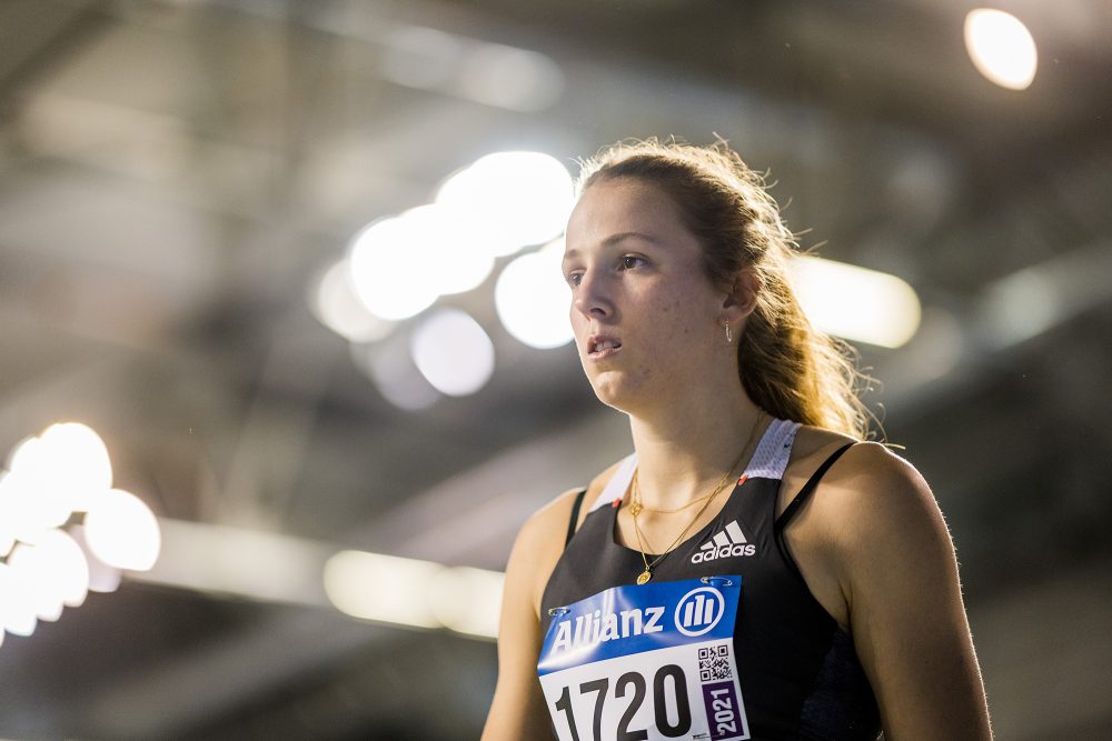 Nahaufnahme von Leichtathletin Hanne Maudens, sie steht im Sportdress in einer beleuchteten Halle