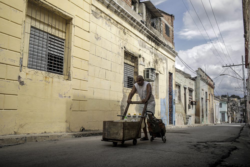 Ein Mann transportiert Wasservorräte in Kanistern auf einem Karren