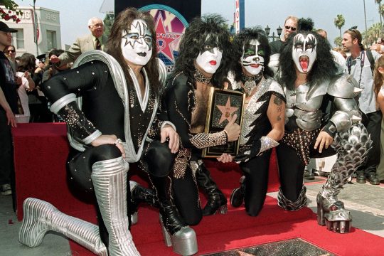 Ace Frehley kniet zusammen mit seinen Kiss-Bandkollegen Paul Stanley, Peter Criss und Gene Simmons auf einem roten Teppich auf dem Hollywood Walk Of Fame