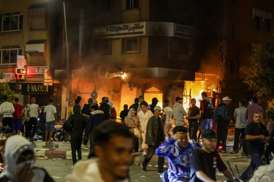 Junge Demonstranten vor einem brennenden Bank-Gebäude