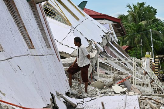 Ein Mann vor einem zerstörten Haus nach dem Erdbeben auf den Philippinen