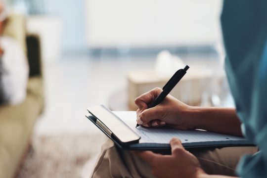 Psychologe macht sich Notizen während einer Sitzung mit einem Patienten