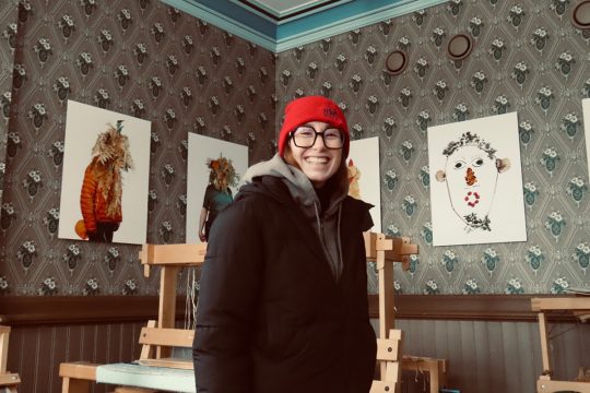 Eine lächelnde Romy vor ausgestellten Kunstwerken