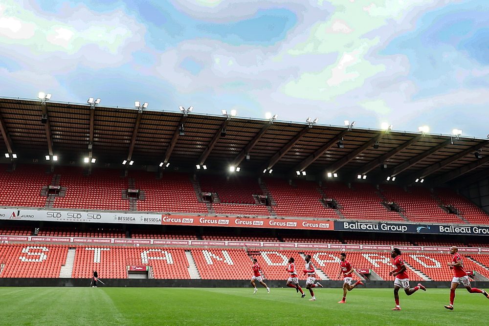 Standard-Spieler laufen über den Rasen im leeren Stadion