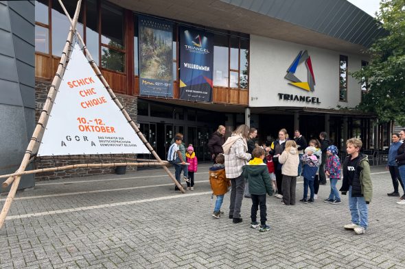 Menschen vor dem Eingang des Triangel St. Vith neben dem Plakat von "Schick.Chic.Chique"