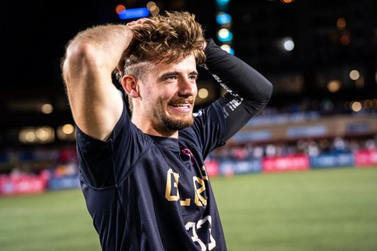 Tobe Decraene auf dem Spielfeld, er hält die Hände entspannt hinter den Kopf und lächelt