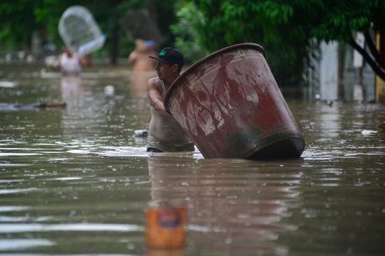 Ein Mann watet nach starken Regenfällen in Poza Rica durch eine überflutete Straße.