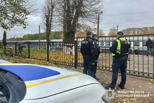 Ukrainische Polizisten, hinter der Absperrung ein Zug