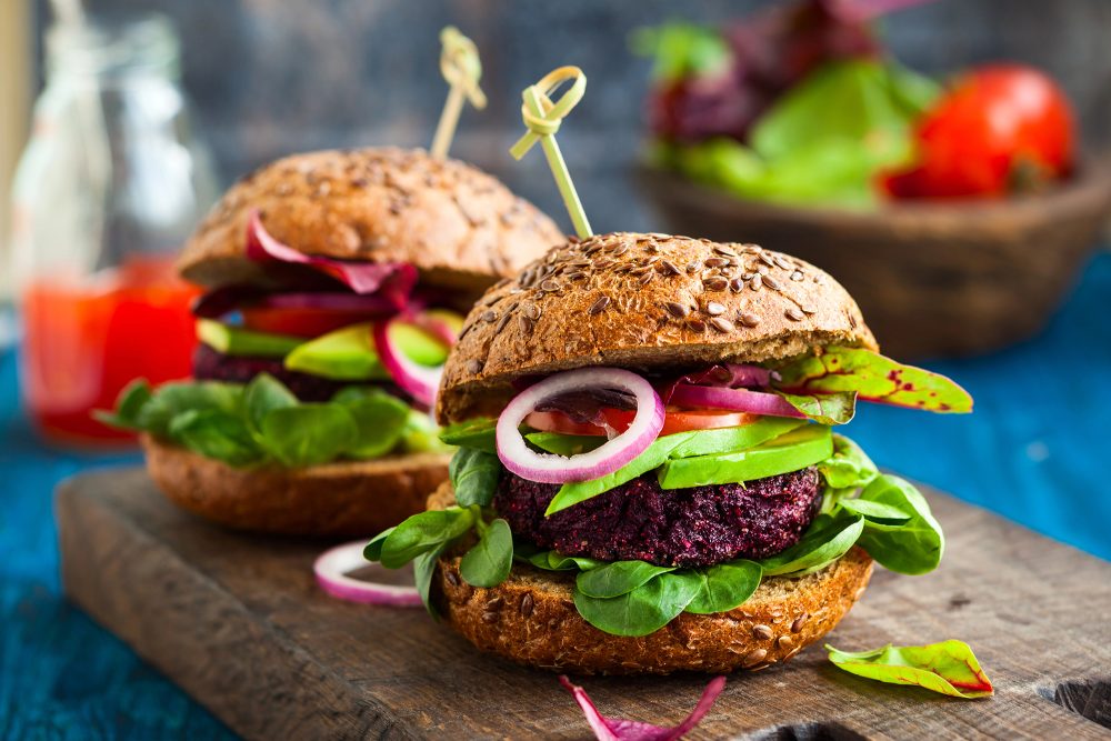 Zwei Veggie-Burger mit Beilagen auf einem Servierbrettchen