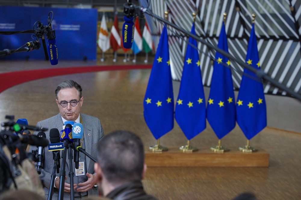 Bart De Wever gibt ein Interview vor dem EU-Gipfel in Brüssel, im Hintergrund Europa-Fahnen