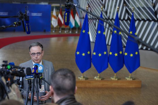 Bart De Wever gibt ein Interview vor dem EU-Gipfel in Brüssel, im Hintergrund Europa-Fahnen