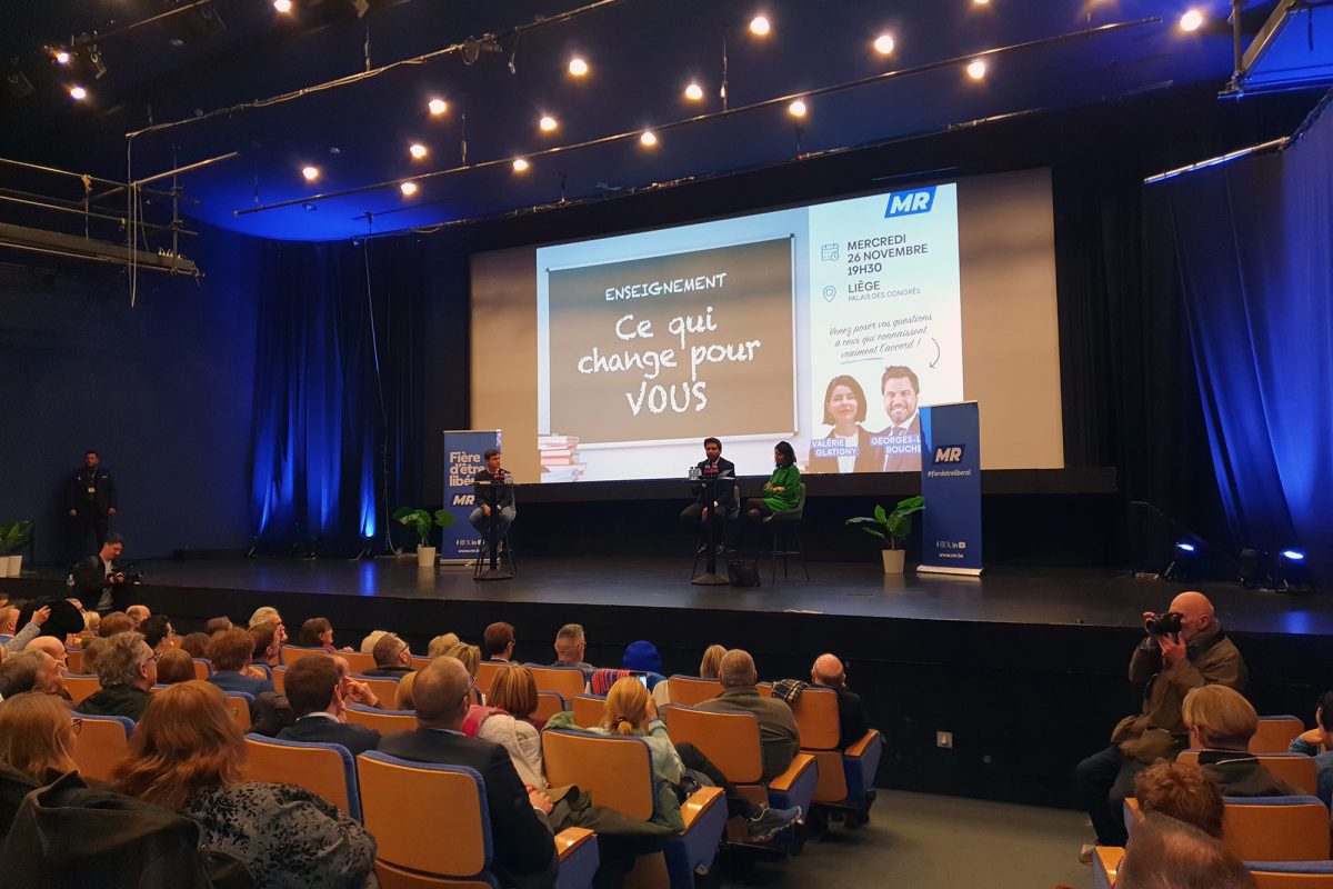 Sitzungssaal mit Besuchern der Veranstaltung der Partei MR, auf der Bühne sind unter anderem George-Louis Bouchez und Valérie Glatigny