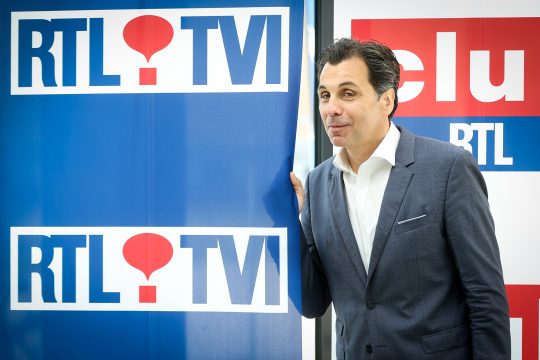 Journalist Christophe Deborsu steht vor Wand mit RTL-tvi-Logo