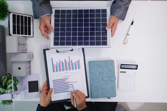 Experte und Kunde sitzen am Tisch und beugen sich über Tabellen und Grafiken