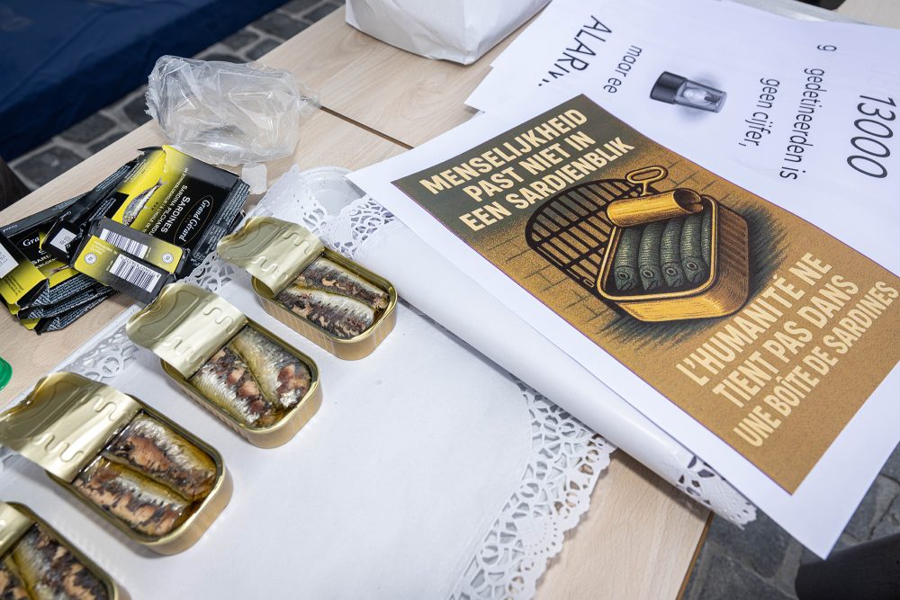 Sardinenbüchsen und Flyer mit dem Slogan "Menschlichkeit passt nicht in eine Sardinenbüchse" auf einem Tisch