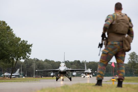 F16-Kampfjet auf der Startbahn in Kleine-Brogel, vorne im Bild steht mit dem Rücken zur Kamera ein Soldat