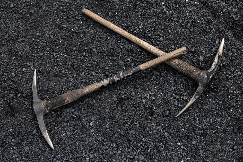 zwei Spitzhacken liegen auf einem Bett aus Kohle