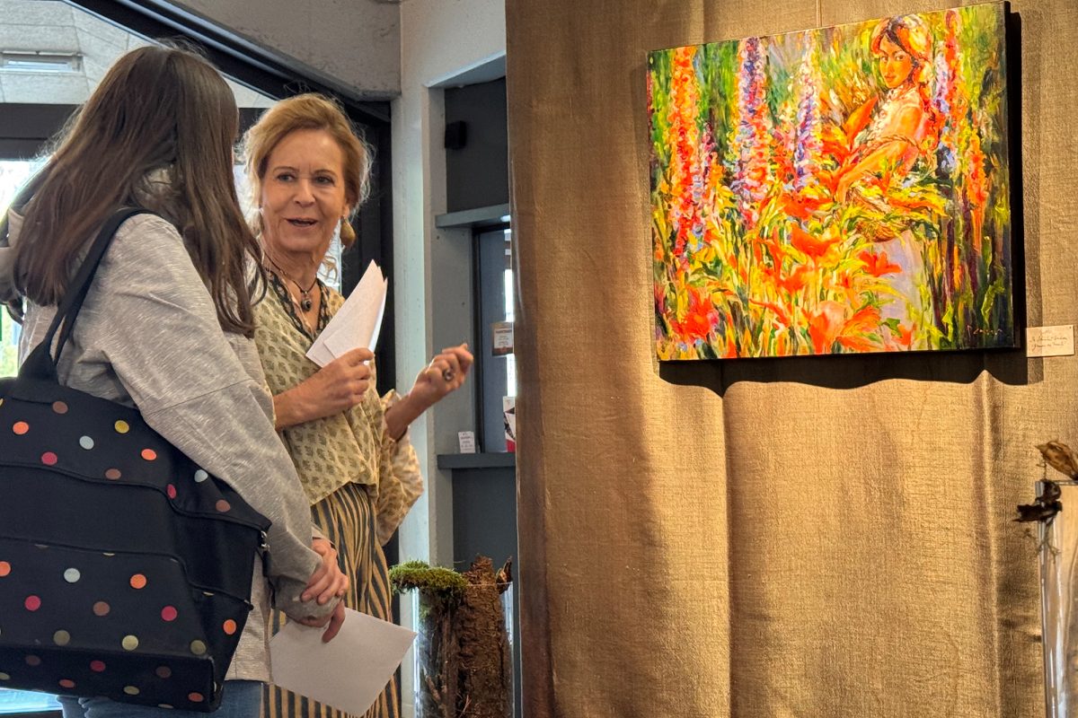 Mona Etienne im Gespräch mit einer Besucherin vor einem ihrer Gemälde