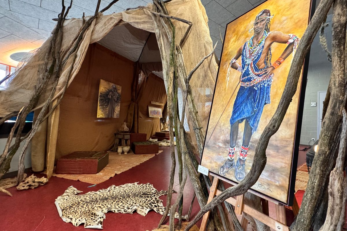 Vor einem Zelt steht auf einer Staffelei ein Gemälde