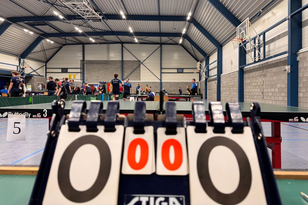 Punktezähler im Vordergrund, im Hintergrund Spieler an den Platten in der Sporthalle