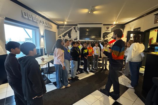 Kinder stehen im Kreis um den Workshop-Leiter herum und hören ihm zu