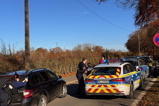 Polizisten stehen für eine Übung mit gezückter Dienstwaffe hinter mehreren Fahrzeugen
