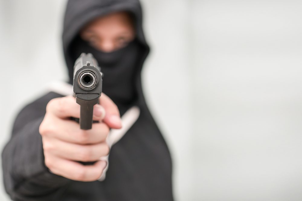 Hand hält Pistole, zielt auf den Betrachter