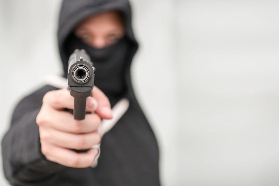 Hand hält Pistole, zielt auf den Betrachter