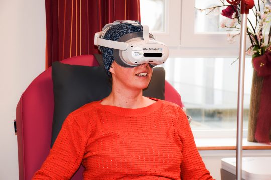 Patientin sitzt mit VR-Brille im Sessel
