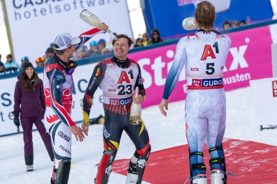 die drei Erstplatzierten begießen sich gegenseitig mit Champagner