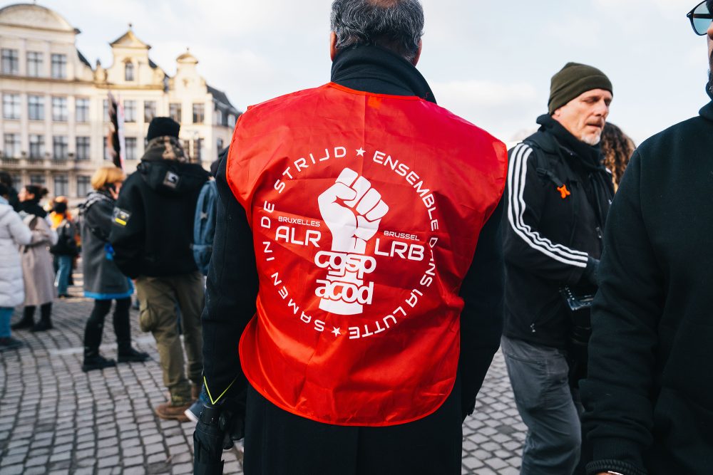 Mann von hinten, er trägt eine Gewerkschaftsweste, bei der hinten eine zum Kampf bereite Faust abgebildet ist