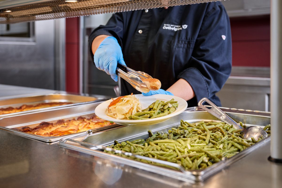 Eine Mitarbeiterin platziert Essen auf einem Teller