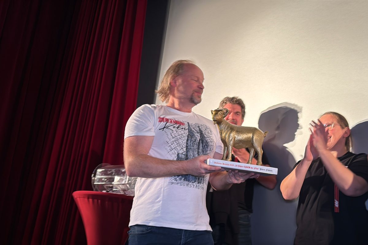 Patric Fohnen hält den "Goldenen Hennes", eine goldene Statue eines Ziegenbocks