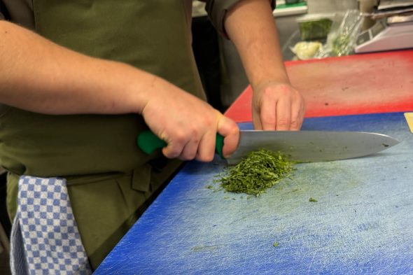 Mitarbeiter schneidet Kräuter in der Küche des Bütgenbacher Hofs